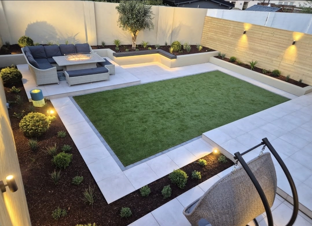 Multi-tier garden design in Malahide, Dublin with outdoor porcelain tiling, composite deck bench, integrated lighting and artificial lawn